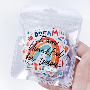 Hand holding holographic vinyl stickers with motivational quotes on white background
