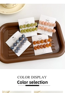 Detail of four colorful jelly-textured heart hair clips on card in a vintage tray