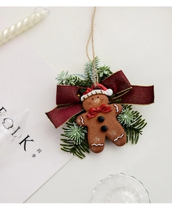 Close-up of resin gingerbread man ornament with red ribbon and pine needles