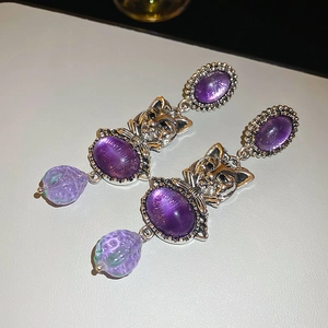 Macro shot of vintage style silver cat earrings with purple strawberry crystals