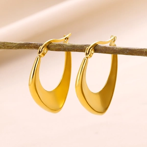 Artistic display of golden U-shaped geometric earrings on a wooden branch detail