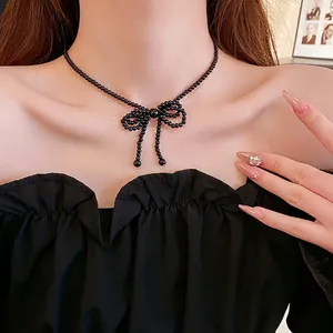 Elegant black beaded necklace featuring a stylish bow pendant on a female model