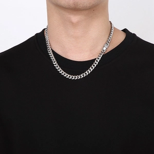 Close-up of a silver Cuban link chain necklace worn by a male model on a white background
