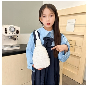 Close-up of white plush lamb wool crossbody chest bag for children in cozy indoor setting