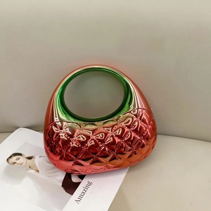 Close-up of metallic red quilted bag with emerald green transparent top on a magazine