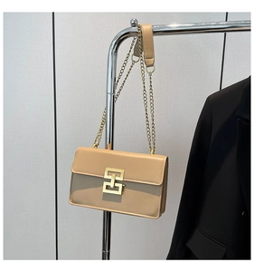 Detailed close-up of a beige rectangular crossbody bag with a golden H-shaped lock