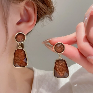 Detail of vintage brown resin earrings with gold metal edges worn by a model