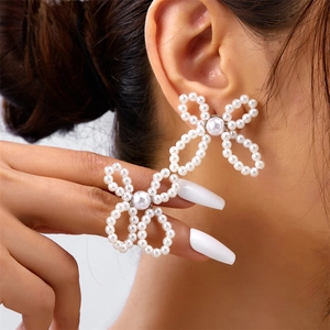 Detail shot of large white faux pearl floral earrings with a unique four-petal flower design