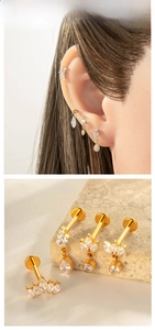 Detail of four gold titanium piercing studs with white zircon on beige stone display