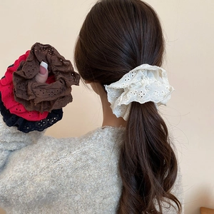 Detailed view of layered hollow lace scrunchies in cream and dark red on a ponytail