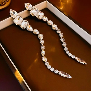 Close-up of silver tassel earrings with clear teardrop crystals on a brown velvet box