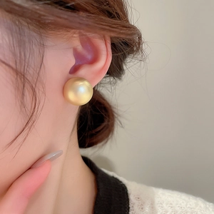 Elegant gold spherical stud earring with matte finish shown on female model ear