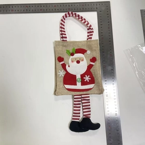 Dettaglio del sacchetto regalo di Natale in iuta con Babbo Natale e manici a strisce rosse