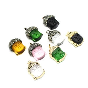 Macro shot of colorful glass Buddha pendants with gold edges and diamond accents
