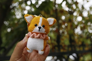 Close-up of handmade crochet Corgi dog keychain with orange fur and pink collar