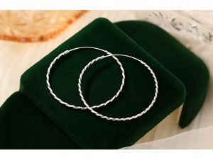 Detail of silver S925 sterling silver hoop earrings with twisted rope texture on green velvet