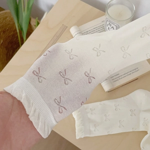 White mesh lace socks with cute bow embroidery and ruffled cuffs on wooden desk