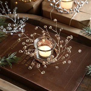 Golden beaded wire wreath candle holder with clear glass cup on vintage books