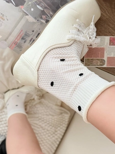 Detail shot of white polka dot socks paired with lace-up shoes in a lifestyle setting