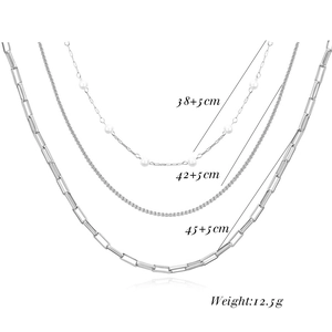 Detailed view of layered necklace set featuring pearls, box chain, and paperclip links