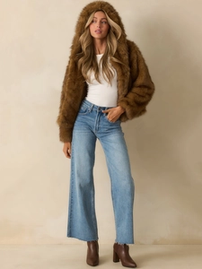 Full view of women's brown faux fur hooded jacket styled with blue wide-leg jeans and boots