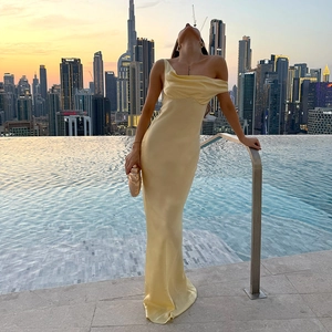 Gros plan sur la texture soyeuse d'une robe en satin jaune devant une piscine de luxe