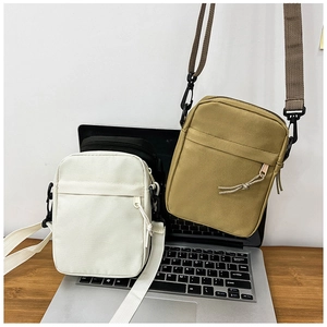 Detailed view of canvas shoulder bags in off-white, black, and khaki on a desk