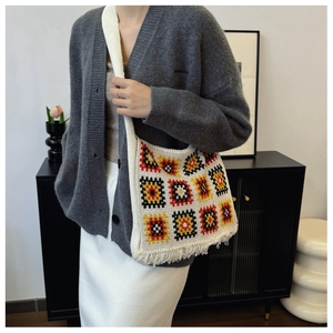 Detail of bohemian granny square knit tote bag featuring colorful geometric patterns and tassels
