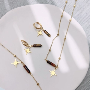 Golden titanium steel jewelry set with tiger eye star pendants on a white plate