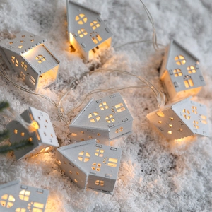 Christmas LED wooden house string lights with warm glow on artificial snow scene