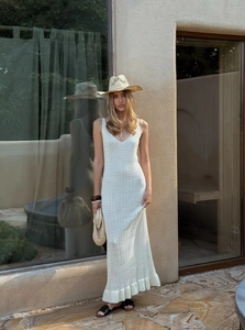 Detail of white hollow-out knit maxi dress with V-neck and ruffle hem in a resort style