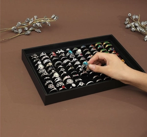 Macro view of 100-slot jewelry display box with vintage rings on brown background