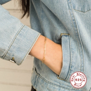 Detail van 925 sterling zilveren paperclip ketting armband in goudkleur om de pols
