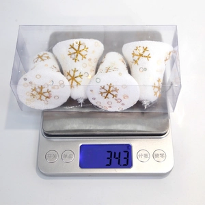 Macro view of four white foam Christmas bells with gold snowflake patterns in a box