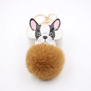 Detail of a brown faux fur ball pendant with a black and white bulldog and gold clasp