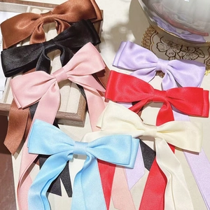 Flat lay of colorful satin bow hair clips in black, pink, and pastel ribbons