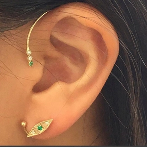 Dettaglio di un piercing in argento 925 con cristallo verde e piccola sfera dorata