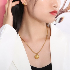 Close-up of a model wearing a gold beaded pendant necklace and matching stud earrings