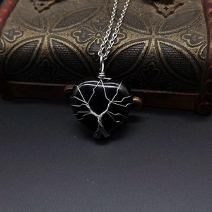 Detail of handmade wire wrapped tree of life pendant with black heart shaped natural stone