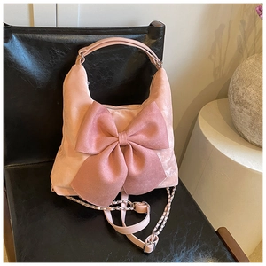 Detail of a pink suede handbag with a large bow and metallic chain strap