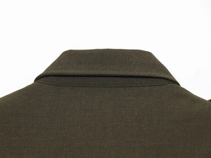 Close-up detail of the padded shoulder stitching and woven fabric on the olive green dress