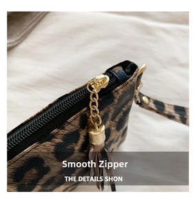 Detail of leopard print clutch showing gold zipper hardware and decorative tassel
