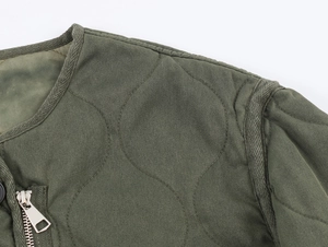Detail of army green quilted jacket featuring onion stitching and silver metal zipper