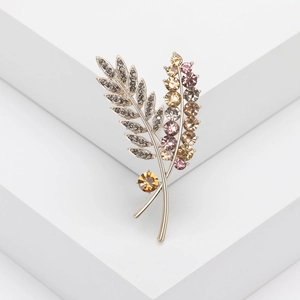 Macro shot of silver feather brooch with amber and pink crystals on geometric stand
