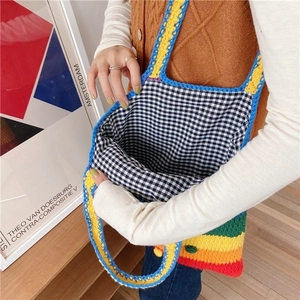 Detail of rainbow striped knit tote bag showing black and white gingham lining and interior