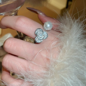 Détail d'une bague ajustable élégante avec fleur en zircon et une grande perle blanche