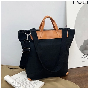 Detail of black canvas tote with brown leather handles and adjustable shoulder strap