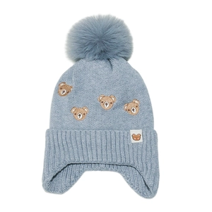 Détail macro du bonnet tricoté bleu clair pour bébé avec broderie ours et pompon doux