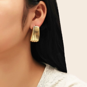 Détail de boucles d'oreilles dorées striées en U portées par un mannequin pour le style