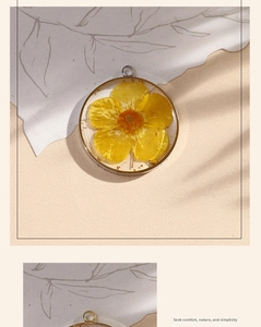 Close-up of handmade resin pendant featuring yellow dried flowers and gold metal frame